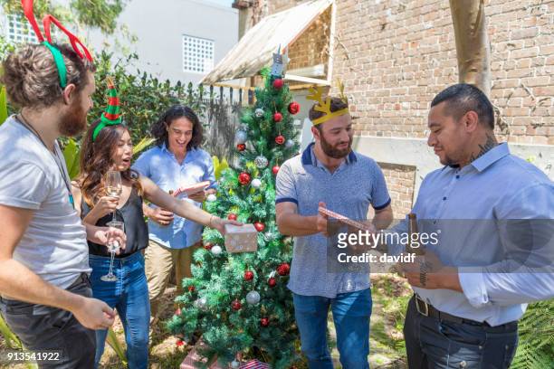 group of mixed race people giving gifts at a christmas party - sydney christmas lights 2017 stock pictures, royalty-free photos & images