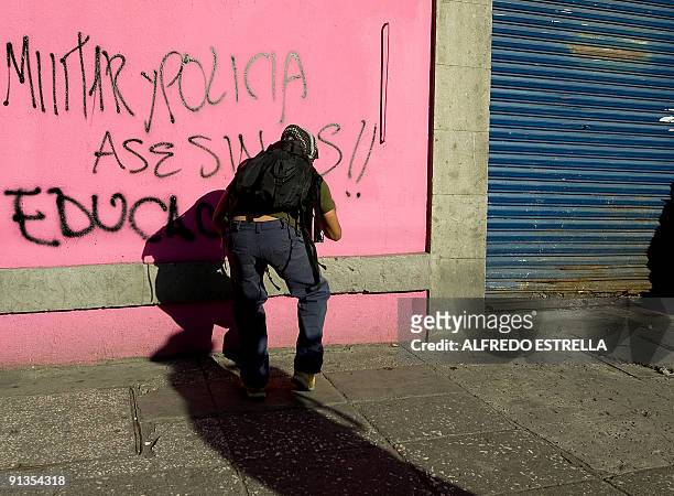 Student spray paints "Military and Police Murderers!!" during a protest on the anniversary of the massacre of Tlatelolco, at the Plaza de las Tres...