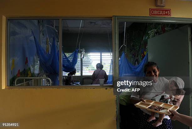 Woman with a baby in arms recevies a tray of food in the children's ward for patients with dengue fever in the La Mascota hospital in Managua on...