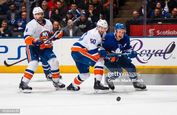 Leo Komarov of the Toronto Maple Leafs battles for the puck with Adam Pelech and Dennis Seidenberg of the New York Islanders during the third period...