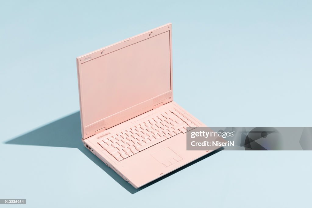 Retro pink laptop on a pastel blue background.