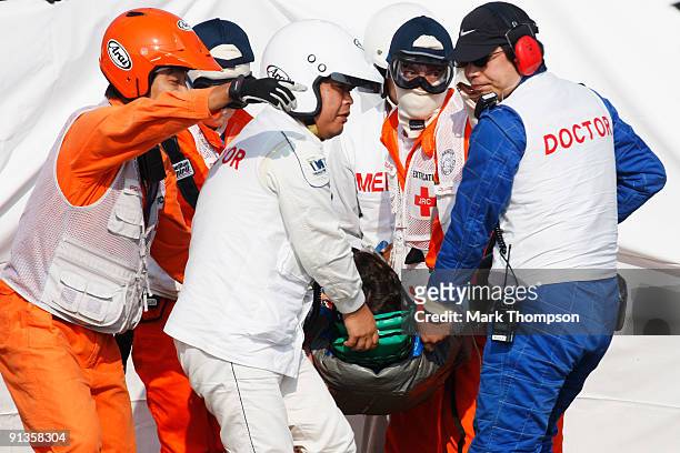 Timo Glock of Germany and Toyota is stretchered away by medical staff and marshalls after crashing during qualifying for the Japanese Formula One...