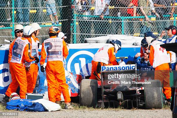 Timo Glock of Germany and Toyota is attended to by medical staff and marshalls after crashing during qualifying for the Japanese Formula One Grand...