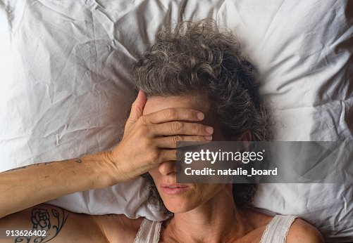 Middle aged woman with hand over eyes on pillow from abvove Middle aged woman with hand over eyes on pillow from abvove