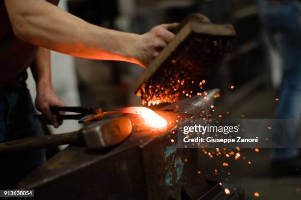 farrier forging horseshoe on anvil - smederij stockfoto's en -beelden