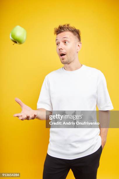 man holding an apple on color background - flip over stockfoto's en -beelden