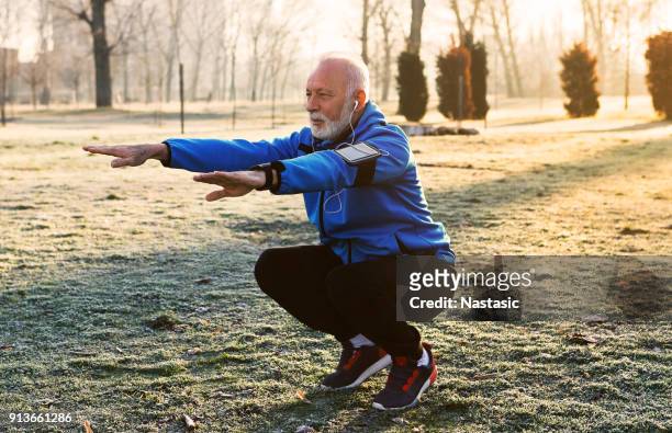 ältere jogger dehnung zu tun - winter sport stock-fotos und bilder