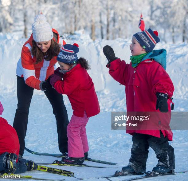 Catherine, Duchess of Cambridge helps a girl who has fallen as she attends an event organised by the Norwegian Ski Federation, where they join local...