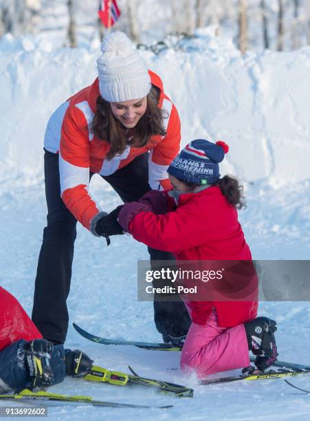 Catherine, Duchess of Cambridge helps a girl who has fallen as she attends an event organised by the Norwegian Ski Federation, where they join local...