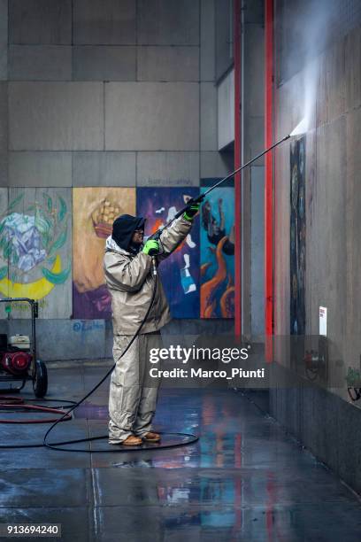 worker cleans the wall from graffiti - cleaning graffiti stock pictures, royalty-free photos & images