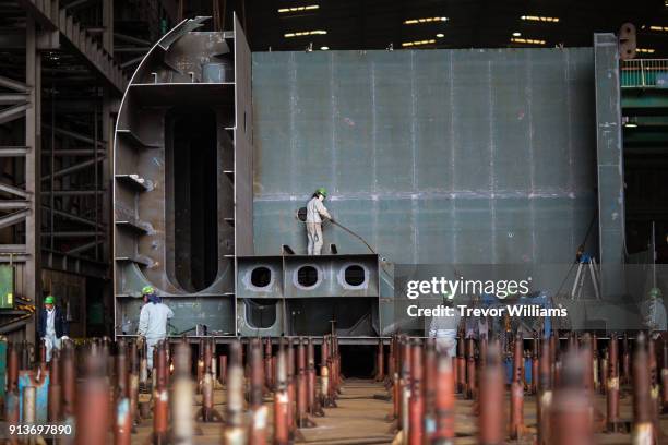 men working in a large shipbuilding factory - cantiere navale foto e immagini stock