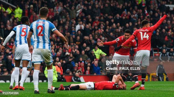 Players react as Manchester United's English midfielder Scott McTominay lies injured on the floor after colliding with Huddersfield Town's Swiss-born...