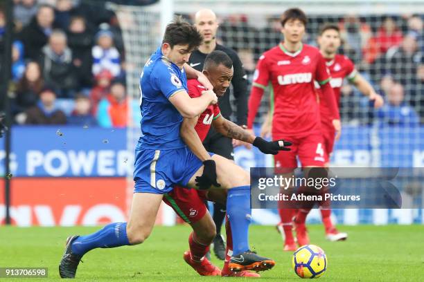 Jordan Ayew of Swansea is challenged by Harry Maguire of Leicester City during the Premier League match between Leicester City and Swansea City at...