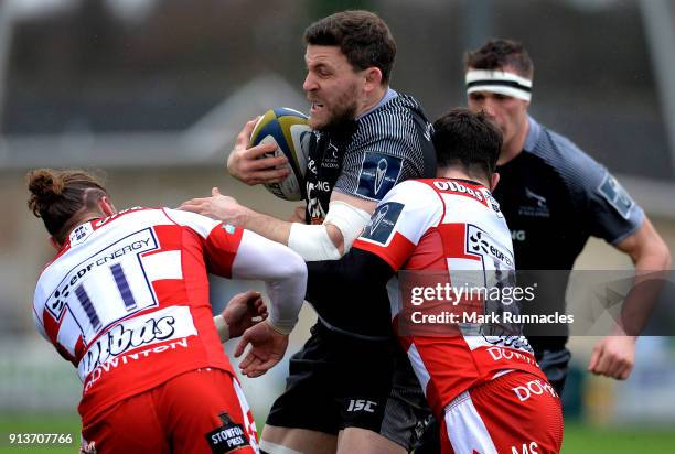 Mark Wilson of Newcastle Falcons is tackled by Matt Scott and Henry Purdy of Gloucester Rugby during the Anglo-Welsh Cup match between Newcastle...