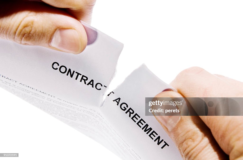 Hands ripping contract agreement document