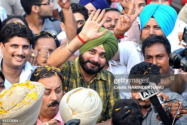 Indian cricketer-turned-politician and Bharatiya Janata Party Member of Parliament Navjot Singh Sidhu gestures while surrounded by supporters upon...
