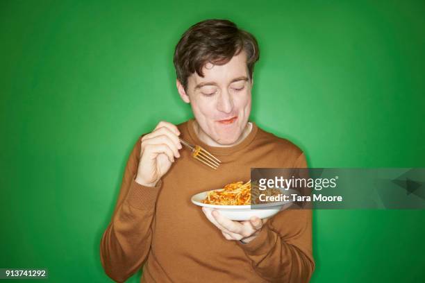 man eating bowl of pasta - indulgence photos et images de collection
