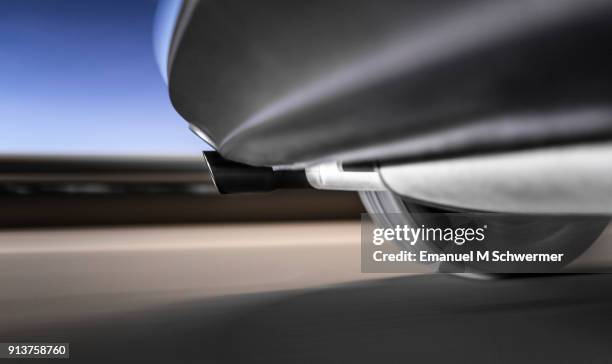 long exposure photograph of a driving car with the exhaust system and the left rear tire prominent in frame, background is motion blurred and streaking. - parachoques fotografías e imágenes de stock