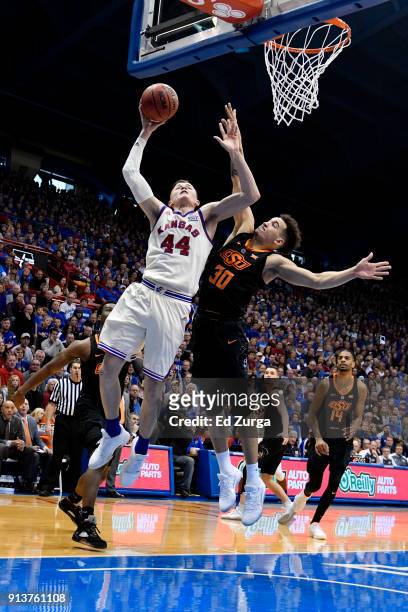Mitch Lightfoot of the Kansas Jayhawks lays the ball up against Jeffrey Carroll of the Oklahoma State Cowboys in the first half at Allen Fieldhouse...