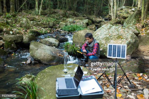 ein wissenschaftler, die überwachung der wasserqualität von einem solar betriebenen feldlabor - umweltschutzbeauftragter stock-fotos und bilder