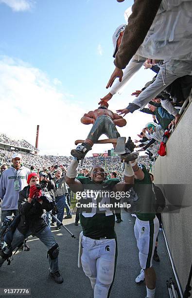 Brendan Gibbons of the Michigan State Spartans hoists the Paul Bunyan trophy awarded to the winning team each year after the Spartans defeated the...