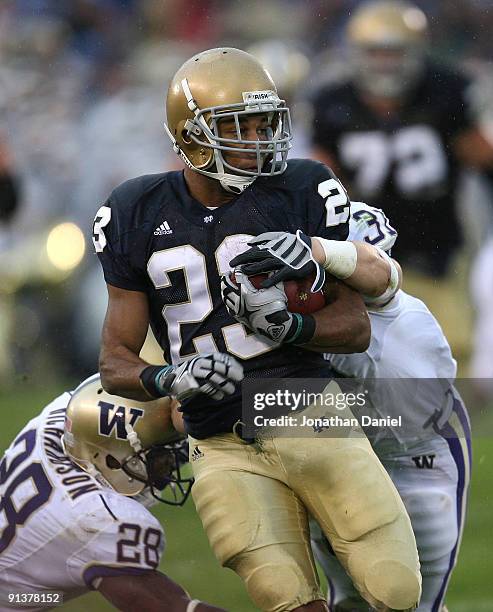 Golden Tate of the Notre Dame Fighting Irish breaks away from Quinton Richardson and Cort Dennison of the Washington Huskies on his way to a 67 yard...