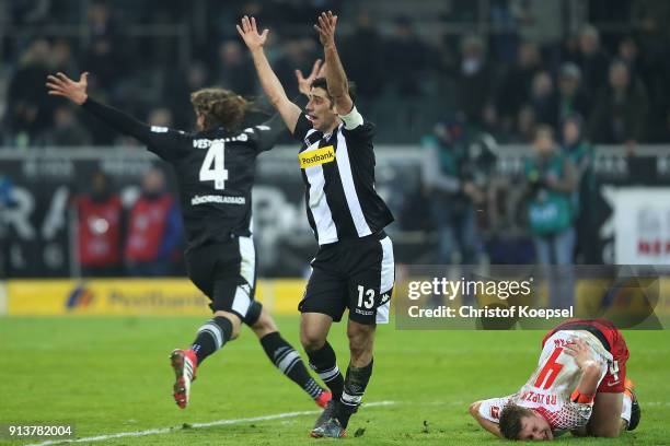 Lars Stindl of Moenchengladbach raises his arms questioning a hand-ball, as Willi Orban of Leipzig lies on the pitch in pain and Jannik Vestergaard...