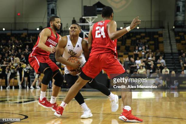 Taylor of the UCF Knights gets fouled by Breaon Brady and Galen Robinson Jr. #25 of the Houston Cougars during a NCAA basketball game at the CFE...