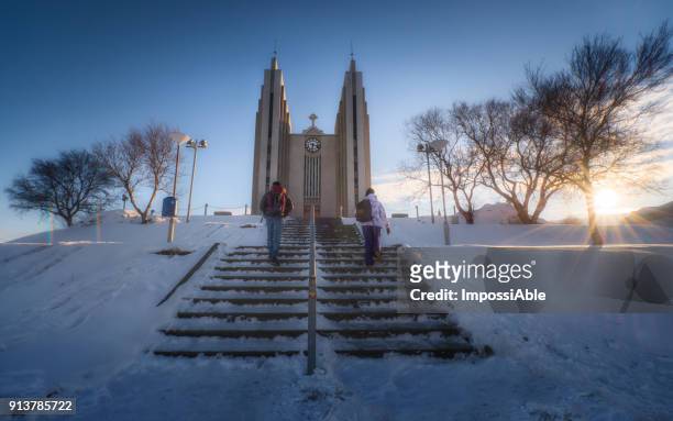couple stepping upstairs to akureyrarkirkja church at sunset - impossiable fotografías e imágenes de stock