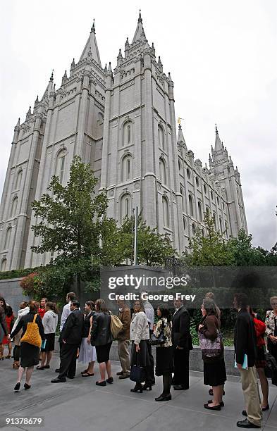 People stand in front of the Mormon Salt Lake temple waiting for the second session of the 179th Semi-Annual General Conference of the church on...