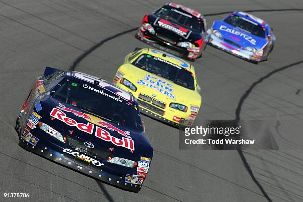 Scott Speed, driver of the Red Bull Toyota, leads Tony Raines, driver of the Long John Silver's Dodge, Robert Richardson Jr., driver of the Mahindra...