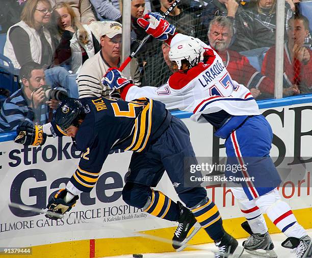 Craig Rivet of the Buffalo Sabres is checked from behind by Georges Laraque of the Montreal Canadiens at HSBC Arena on October 3, 2009 in Buffalo,...