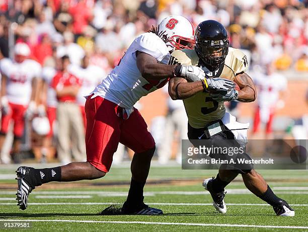 Devon Brown of the Wake Forest Demon Deacons is wrapped up fromk behind by Dwayne Maddox of the North Carolina State Wolfpack at BB&T Field on...