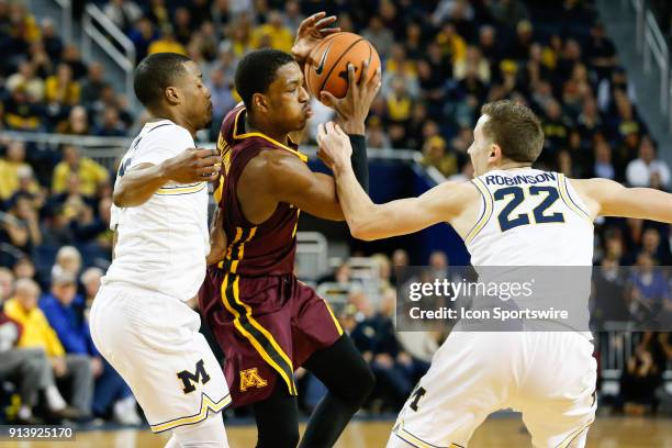 Minnesota Golden Gophers guard Isaiah Washington is defended by Michigan Wolverines guard Duncan Robinson and Michigan Wolverines guard Muhammad-Ali...