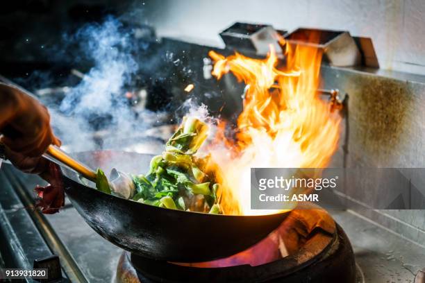 chef in restaurant kitchen at stove with high burning flames - chinese ethnicity stock pictures, royalty-free photos & images