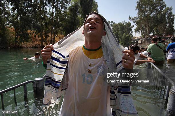 Brazilian Evangelist Christian, who wears a Tallit or Jewish prayer shawl, emerges from the water as he is baptised in the Jordan River on October 4,...