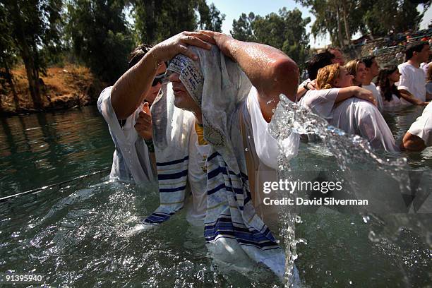 Brazilian Evangelist Christian, who wears a Tallit or Jewish prayer shawl, emerges from the water as he is baptised in the Jordan River on October 4,...