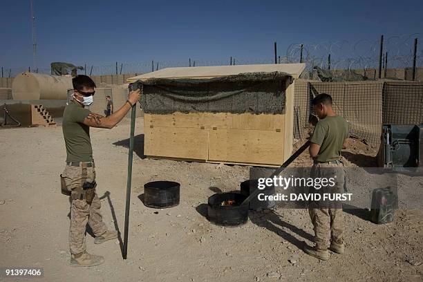 Marines from Military Police Company 2nd Marine Division burn their faeces at the end of the day at their forward operating base in Farah Province,...