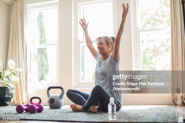 smiling mature woman with hands raised doing yoga - yoga at home stock pictures, royalty-free photos & images