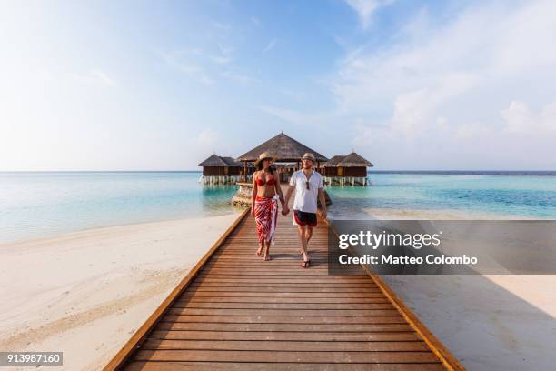 adult couple walking on jetty, maldives - ari atoll stock-fotos und bilder