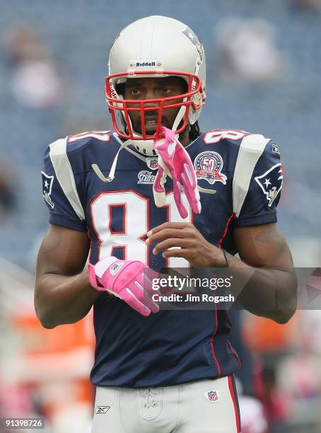 Randy Moss of the New England Patriots adjust his pink gloves, worn to support Breast Cancer Awareness, before a game with the Baltimore Ravens at...