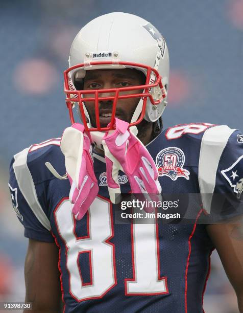 Randy Moss of the New England Patriots adjust his pink gloves, worn to support Breast Cancer Awareness, before a game with the Baltimore Ravens at...