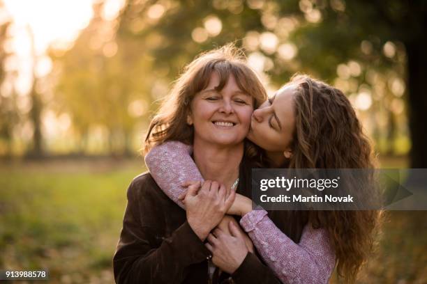 young loving daughter kissing her mother - mother and daughter kissing stock pictures, royalty-free photos & images