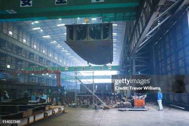 an engineer watching a large piece of a steel being moved with a crane - cantiere navale foto e immagini stock