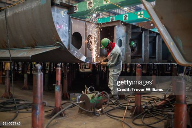 a man welding inside a shipbuilding factory - scheepsbouwer stockfoto's en -beelden