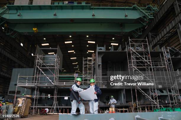 two engineers discuss cargo ship plans in a shipbuilding factory - construtor de navios imagens e fotografias de stock