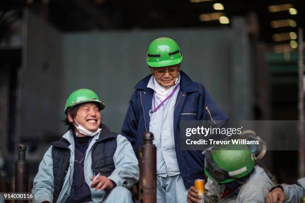 steel workers gathering and laughing during a break from work at a shipbuilding factory - senior blaumann stock-fotos und bilder