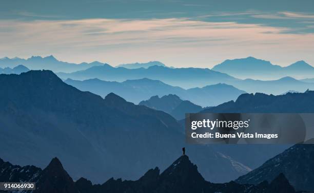 lone climber standing on a peak - meta turistica fotografías e imágenes de stock