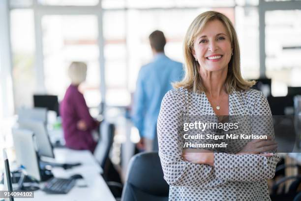 businesswoman with arms crossed in office - 50 years in business stock pictures, royalty-free photos & images