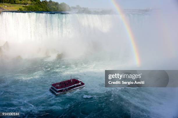 a tour boat very close to niagara falls - tourists visit niagara falls ahead of canadas 150th anniversary celebration stockfoto's en -beelden